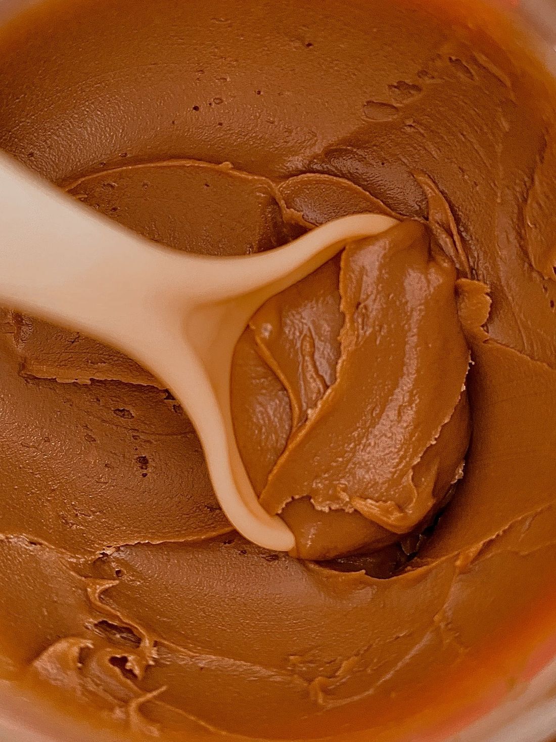 Gros plan sur la crème de caramel au beurre salé Salidou dans son pot, une cuillère plantée dedans